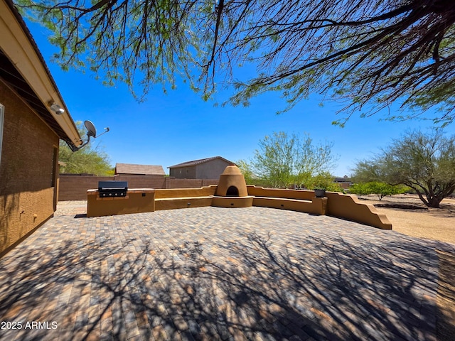 view of yard with a fireplace, a patio area, fence, and an outdoor kitchen