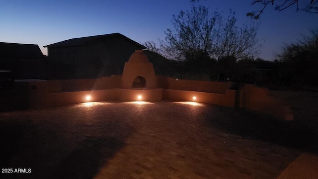 patio terrace at dusk featuring an outdoor fireplace