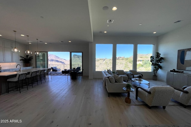 living room featuring light hardwood / wood-style floors, sink, and a mountain view