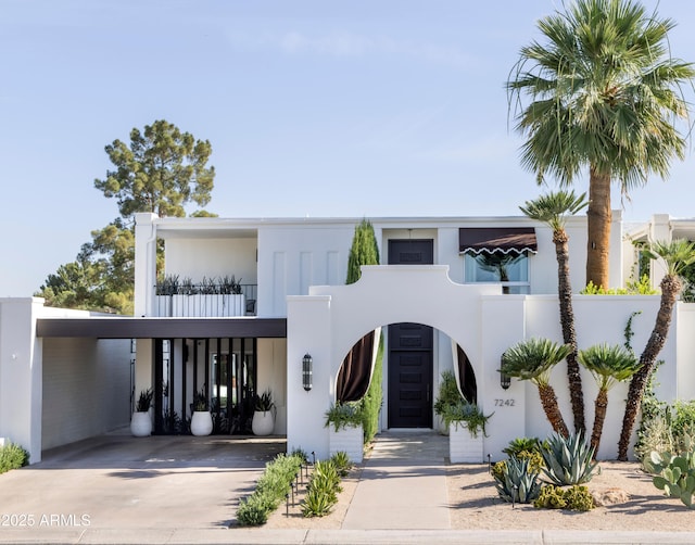 view of front facade with concrete driveway, a carport, and stucco siding