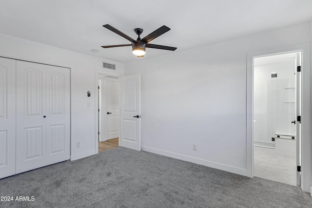 unfurnished bedroom with a closet, light colored carpet, ceiling fan, and connected bathroom