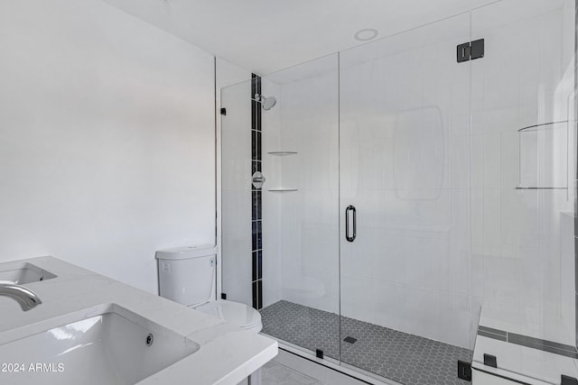 bathroom featuring toilet, a shower with door, and dual sinks