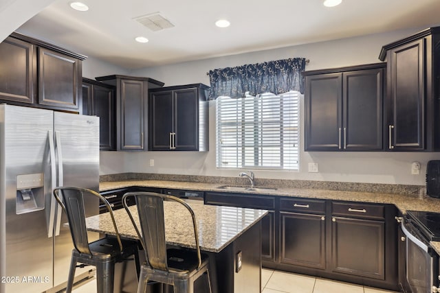 kitchen with sink, a kitchen island, stainless steel refrigerator with ice dispenser, light stone counters, and a kitchen bar