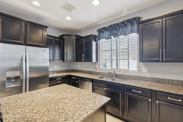 kitchen with light stone countertops, appliances with stainless steel finishes, and sink