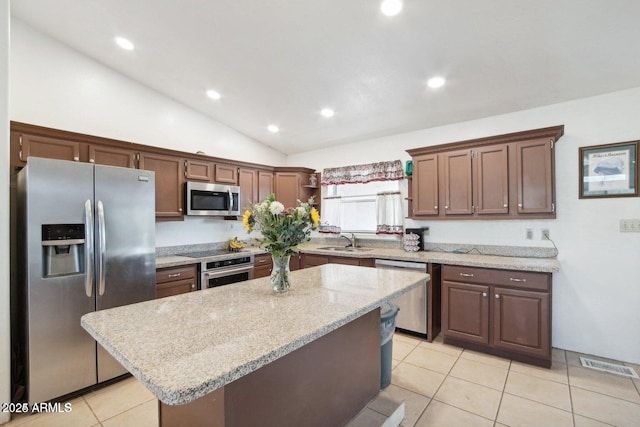 8343 W Calle Lejos, Peoria, AZ 85383 - kitchen featuring appliances with stainless steel finishes, a sink, light tile patterned floors, a kitchen island, and lofted ceiling