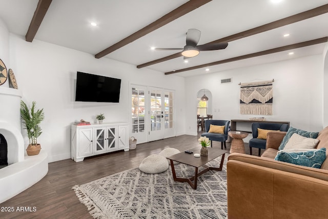 living room featuring ceiling fan, wood-type flooring, and beam ceiling