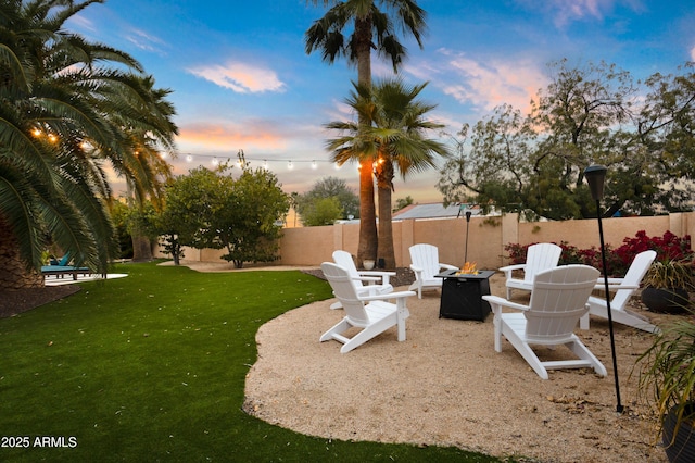 yard at dusk featuring a patio and a fire pit