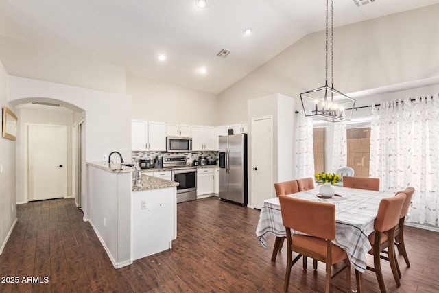 3821 N 125th Dr, Avondale, AZ 85392 - kitchen featuring appliances with stainless steel finishes, high vaulted ceiling, arched walkways, white cabinets, and light stone counters