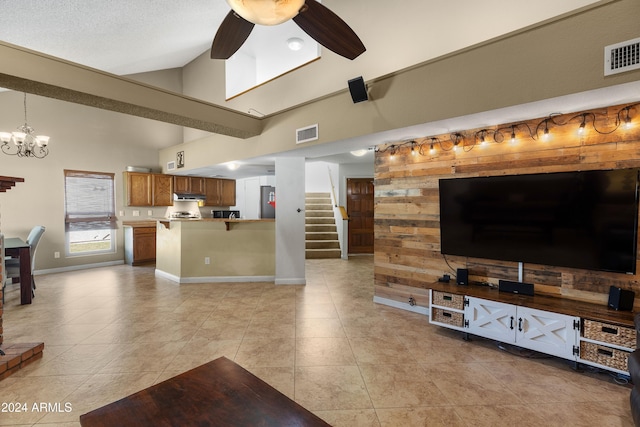 tiled living room with ceiling fan with notable chandelier, a textured ceiling, and high vaulted ceiling