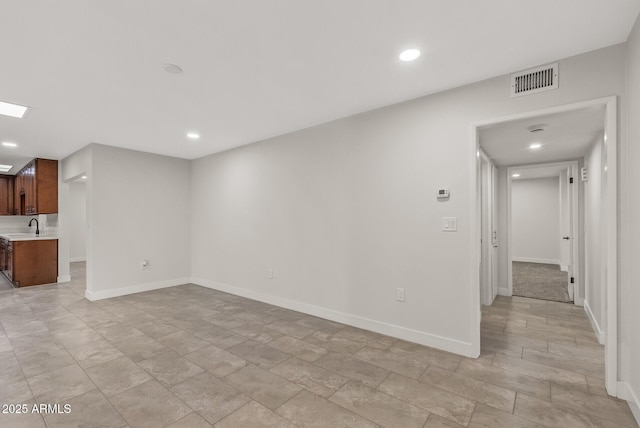 unfurnished living room with baseboards, visible vents, recessed lighting, and a sink