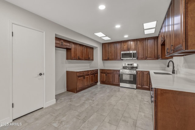 kitchen with light countertops, a skylight, recessed lighting, appliances with stainless steel finishes, and a sink