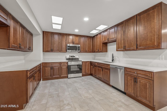 kitchen featuring light countertops, recessed lighting, stainless steel appliances, a sink, and a skylight