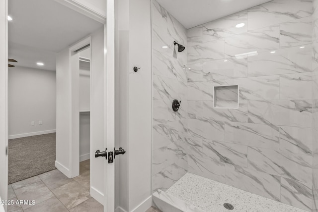 bathroom featuring a spacious closet, baseboards, and a shower stall