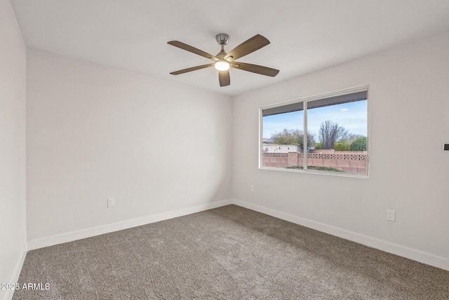 carpeted empty room with a ceiling fan and baseboards