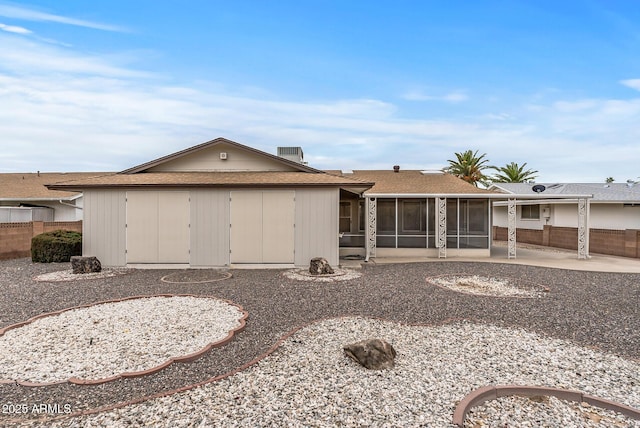 back of property with a patio, a sunroom, fence, and roof with shingles