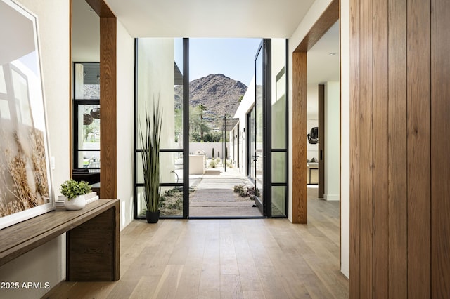 doorway to outside featuring a mountain view, a wall of windows, and wood finished floors