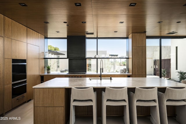 kitchen with light countertops, a breakfast bar area, modern cabinets, and a sink
