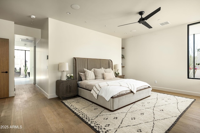 bedroom featuring ceiling fan, light wood-type flooring, visible vents, and baseboards