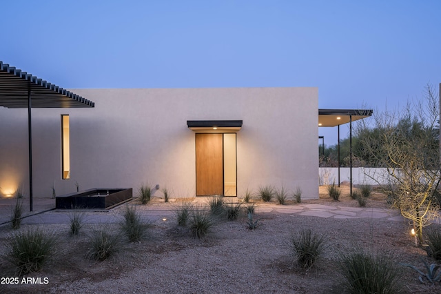 rear view of house with fence and stucco siding