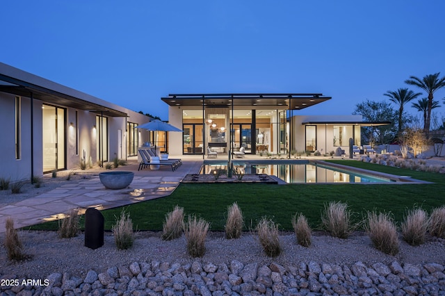 back of property featuring a yard, an outdoor pool, and a patio
