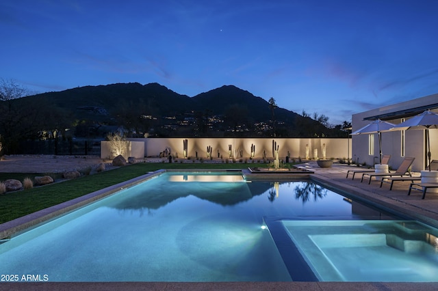view of pool featuring a pool with connected hot tub, a patio, a fenced backyard, and a mountain view