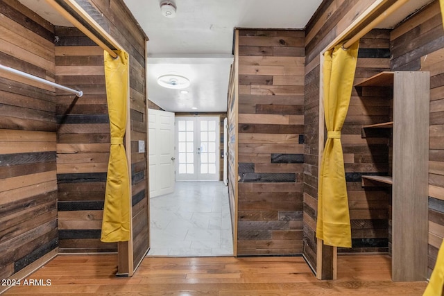 hallway with hardwood / wood-style floors, french doors, and wood walls