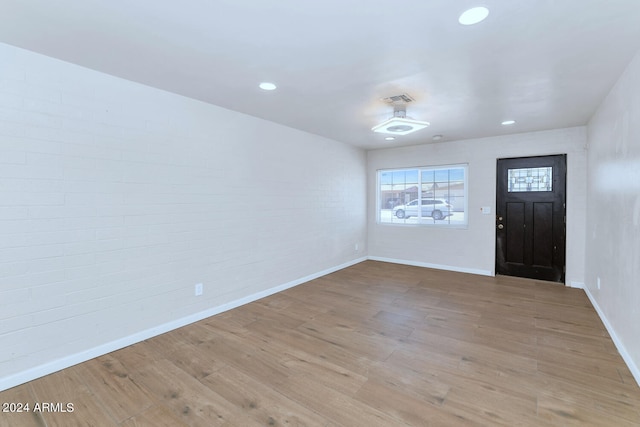 entryway with wood-type flooring and brick wall