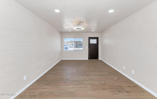 entrance foyer with hardwood / wood-style floors and brick wall