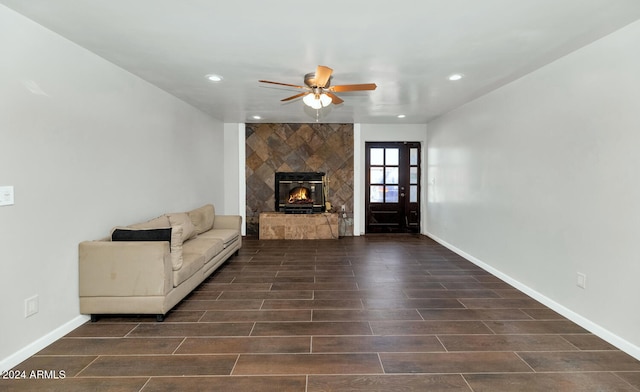 unfurnished living room featuring dark hardwood / wood-style flooring, ceiling fan, and a tiled fireplace