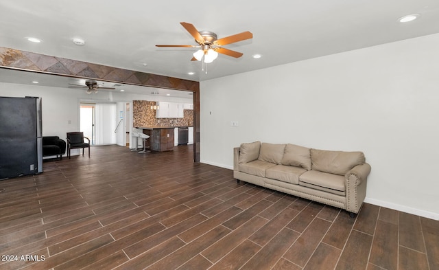 living room with ceiling fan and dark wood-type flooring