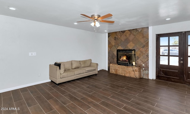 living room with a tiled fireplace, ceiling fan, and dark hardwood / wood-style floors