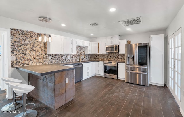 kitchen featuring white cabinetry, dark wood-type flooring, stainless steel appliances, and decorative light fixtures