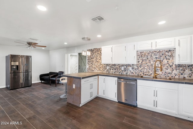 kitchen with appliances with stainless steel finishes, white cabinetry, dark wood-type flooring, and sink