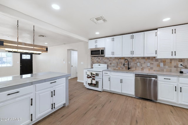 kitchen with white cabinetry, sink, stainless steel appliances, decorative backsplash, and light wood-type flooring