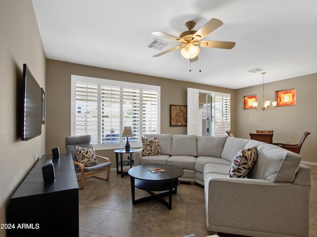 tiled living room with ceiling fan with notable chandelier