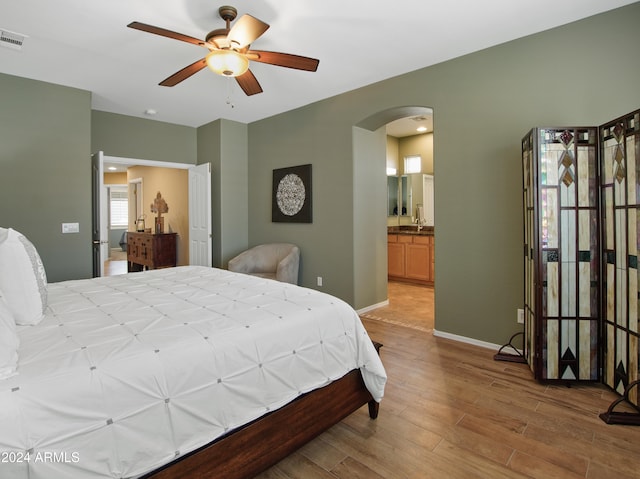 bedroom with ceiling fan, light hardwood / wood-style flooring, ensuite bathroom, and sink