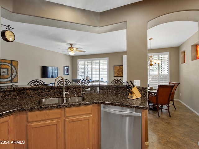 kitchen featuring dishwasher, ceiling fan with notable chandelier, dark stone counters, and sink