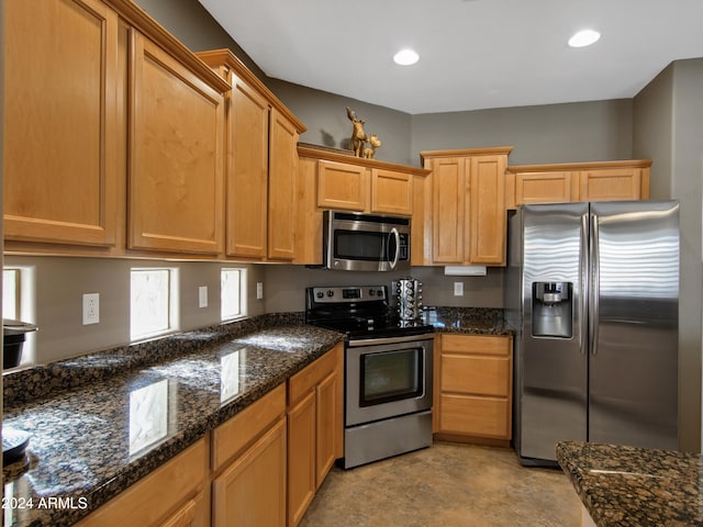 kitchen with appliances with stainless steel finishes and dark stone counters