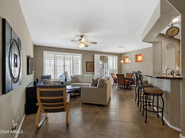 tiled living room featuring ceiling fan with notable chandelier