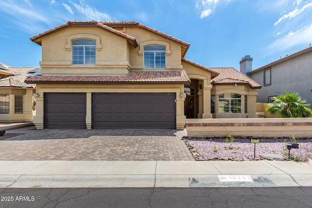 mediterranean / spanish house with fence, an attached garage, a tile roof, stucco siding, and driveway