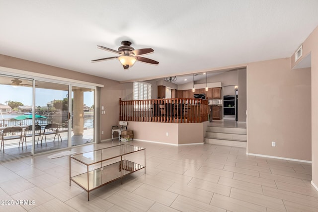 living room with ceiling fan, visible vents, and baseboards
