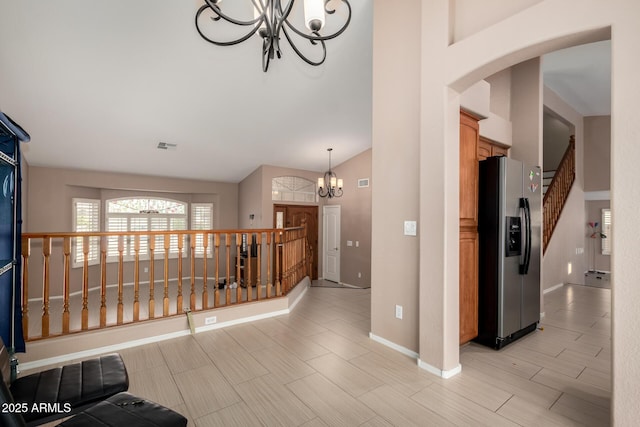hall with baseboards, arched walkways, a notable chandelier, and high vaulted ceiling