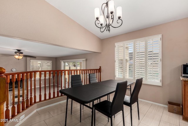 dining space with baseboards, ceiling fan with notable chandelier, and lofted ceiling