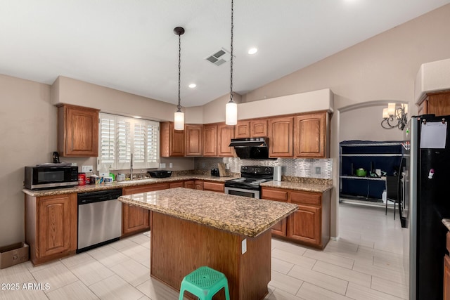 kitchen featuring brown cabinets, a sink, stainless steel appliances, a kitchen island, and visible vents