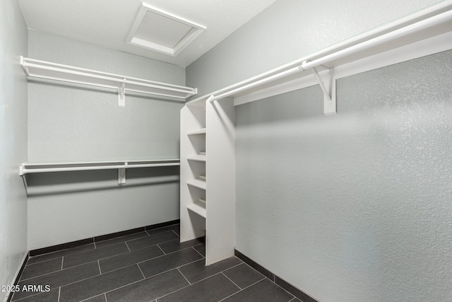 walk in closet with dark tile patterned flooring and attic access