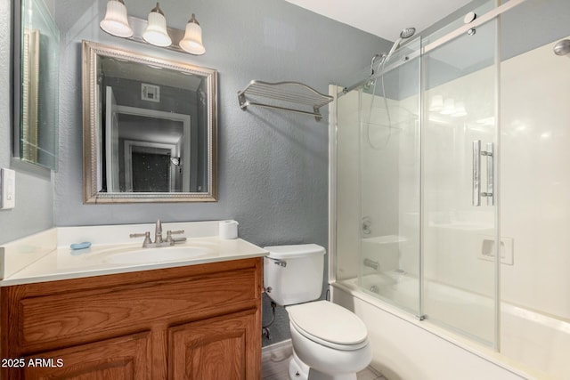 bathroom with visible vents, vanity, bath / shower combo with glass door, toilet, and a textured wall