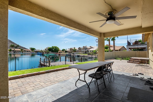 view of patio / terrace featuring a water view, ceiling fan, a residential view, and a fenced backyard