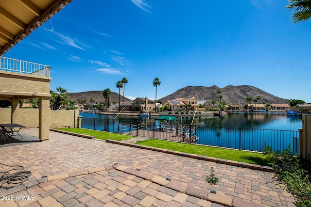 view of patio featuring a water and mountain view, fence, and a balcony