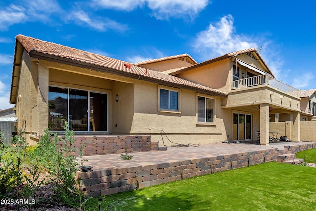 rear view of house with a tiled roof, a patio, a balcony, and stucco siding