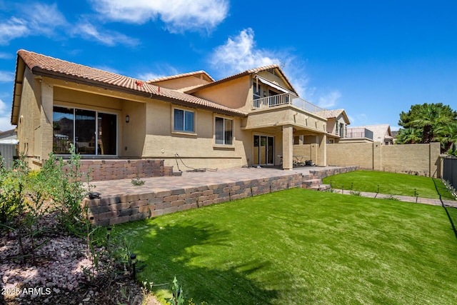 back of house with fence, a balcony, a yard, a patio, and stucco siding